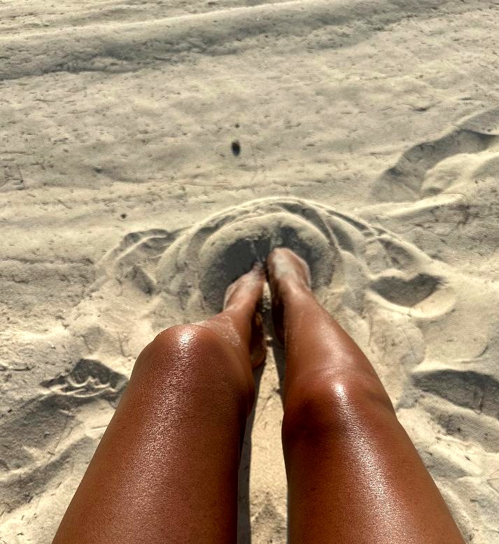 Luminous bronzed skin on white sand
